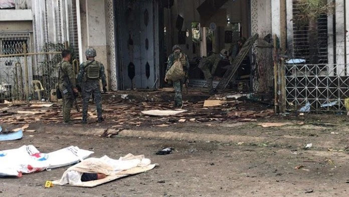 Philippine army soldiers walk near covered bodies as they inspect damage outside the Cathedral of Our Lady of Mount Carmel following a bomb blast in Jolo Jan. 27, 2019. The explosion, just before morning Mass, killed at least 20 people and wounded dozens of others.